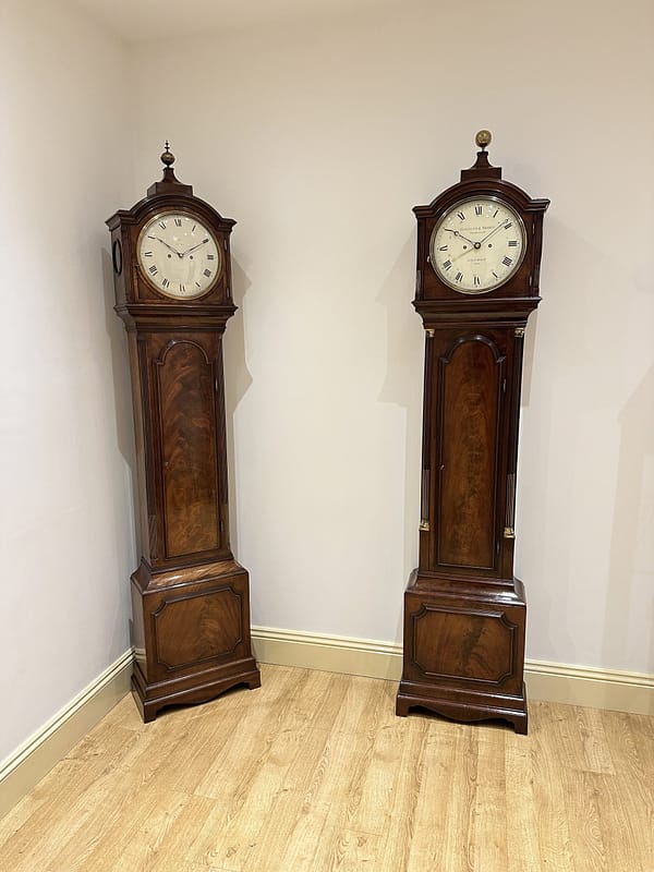 georgian-longcase-clock-handley-moore-london -showroom image of two very similar georgian london longcase clock with convex painted round dial and fine quality mahogany cases.