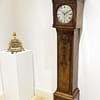 london-walnut-quarter-chiming-longcase-grandfather-clock-showroom-view A high quality, small proportioned, Westminster chiming longcase / grandfather clock by Maple of London. Image of the clock in a showroom setting next to a french mantel clock