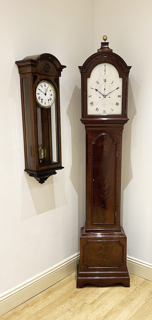 recordon-london-georgian-mahogany-longcase-grandfather-clock-showroom-view Image of the flame mahoagny georgian longcase clock next a walnut wall regulator in Story Antique Clocks showroom