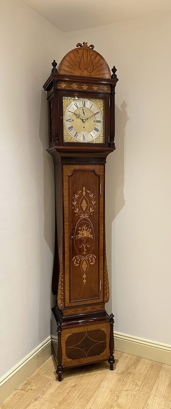 smith-london-quarter-chiming-longcase-clock-showroom2 An image of a fine quality mahogany inlaid Sheraton style clock in a showroom setting