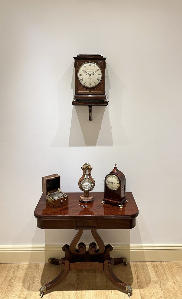 rosewood-bracket-clock-adams-london-showroom showroom image of antique bracket clock and mantel clock display on a Regency card table